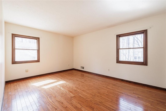 unfurnished room featuring visible vents, baseboards, and hardwood / wood-style flooring