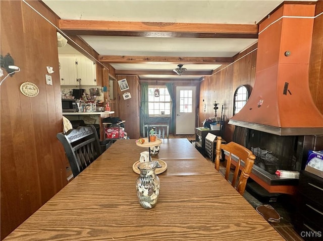 dining space featuring beamed ceiling and wooden walls