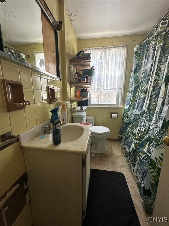 full bathroom with backsplash, toilet, vanity, a shower with curtain, and tile walls