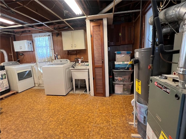 washroom with wood walls, light floors, washer and dryer, cabinet space, and a sink