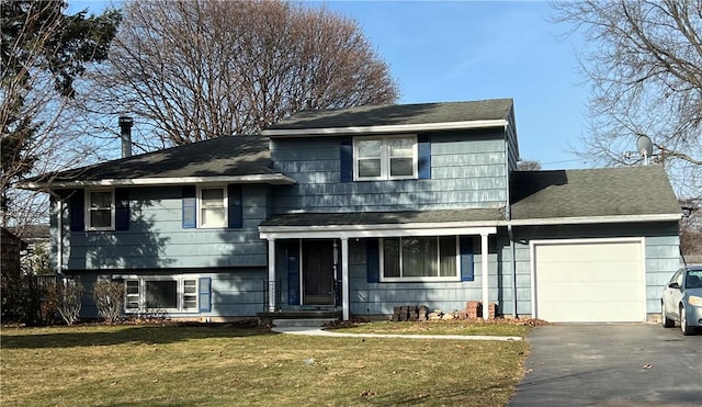 tri-level home with a garage, roof with shingles, a front yard, and aphalt driveway