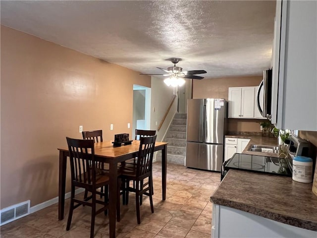 dining room featuring visible vents, baseboards, stairs, a textured ceiling, and a ceiling fan