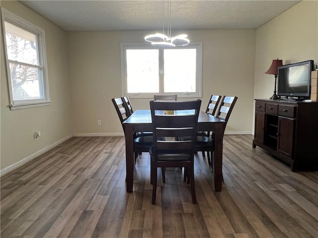 dining space with a notable chandelier, dark wood-style floors, baseboards, and a textured ceiling