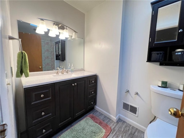 full bath with visible vents, toilet, baseboards, and wood finished floors