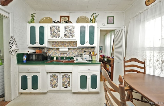 kitchen with glass insert cabinets, white cabinets, and black microwave