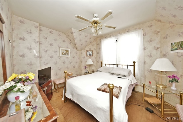 bedroom featuring wallpapered walls, a ceiling fan, and wood finished floors