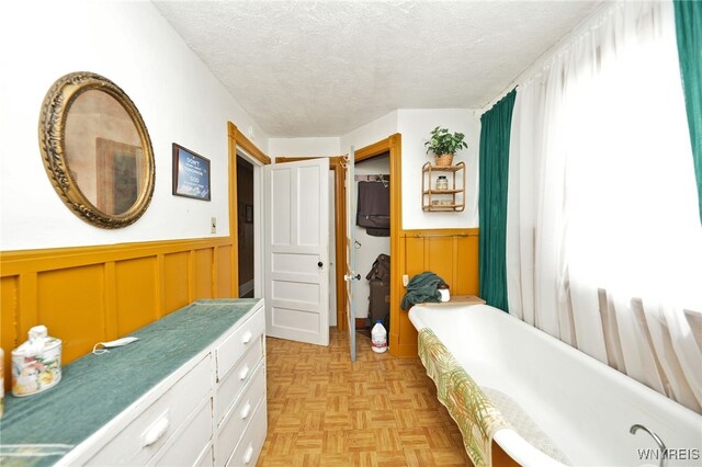 bedroom with a textured ceiling and wainscoting