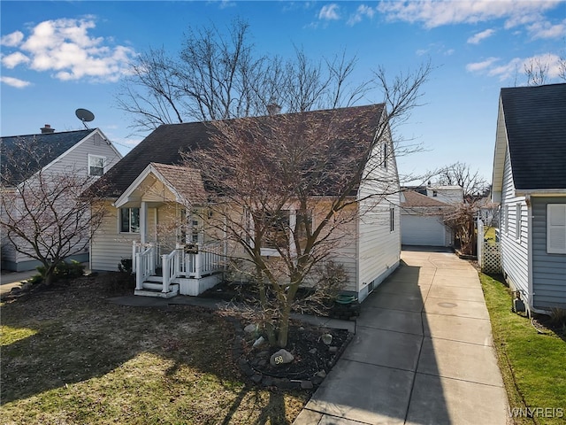 view of front of property featuring a detached garage, roof with shingles, an outdoor structure, and driveway