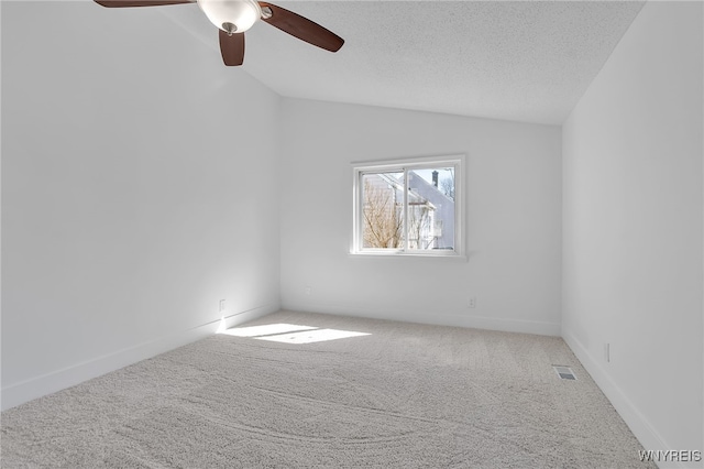 carpeted spare room featuring visible vents, a textured ceiling, baseboards, ceiling fan, and vaulted ceiling