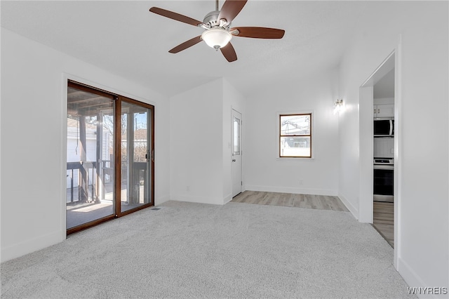 unfurnished living room featuring light carpet, baseboards, lofted ceiling, and ceiling fan