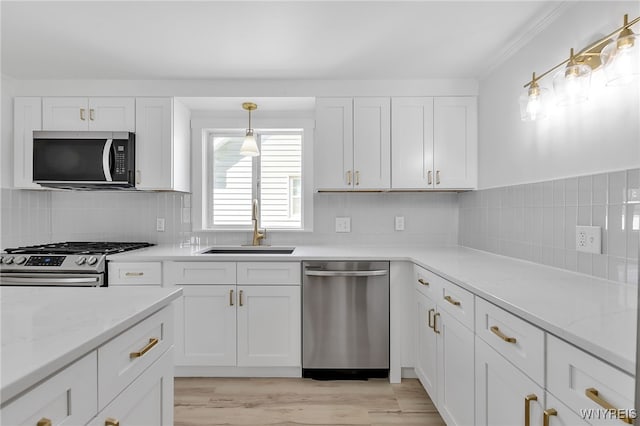 kitchen featuring decorative backsplash, white cabinetry, stainless steel appliances, and a sink