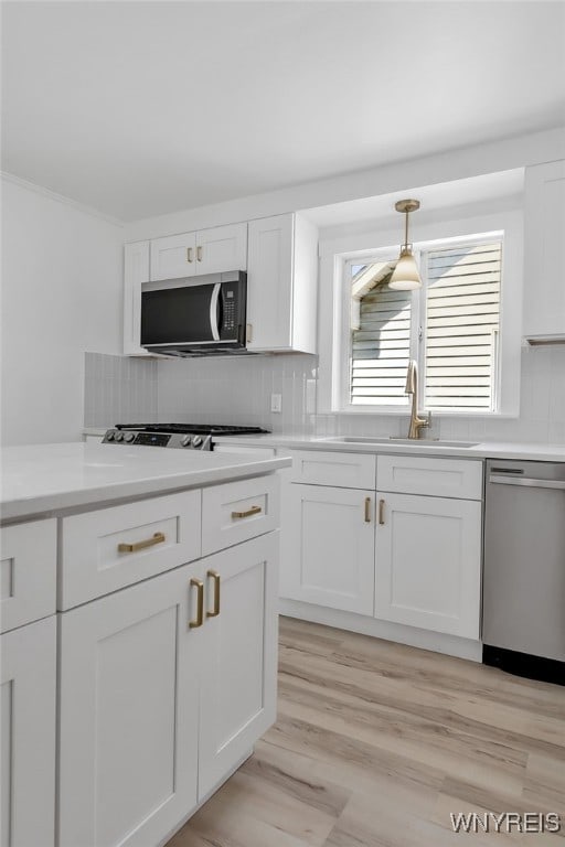 kitchen featuring a sink, stainless steel appliances, decorative backsplash, and white cabinetry