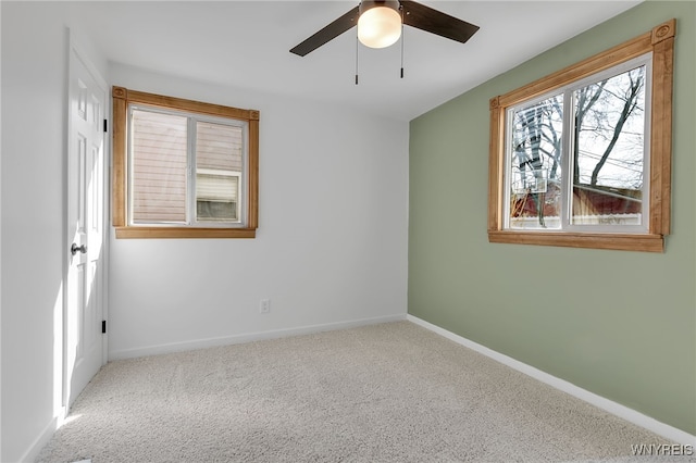 carpeted empty room featuring a ceiling fan and baseboards