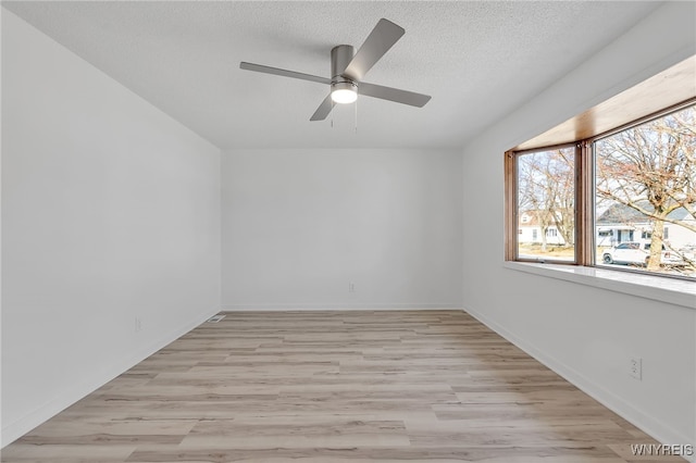 unfurnished room featuring baseboards, a ceiling fan, light wood-style floors, and a textured ceiling