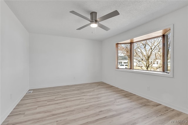 unfurnished room featuring a ceiling fan, baseboards, light wood finished floors, and a textured ceiling