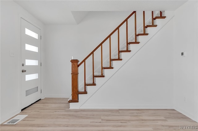 foyer entrance featuring stairway, wood finished floors, visible vents, and baseboards