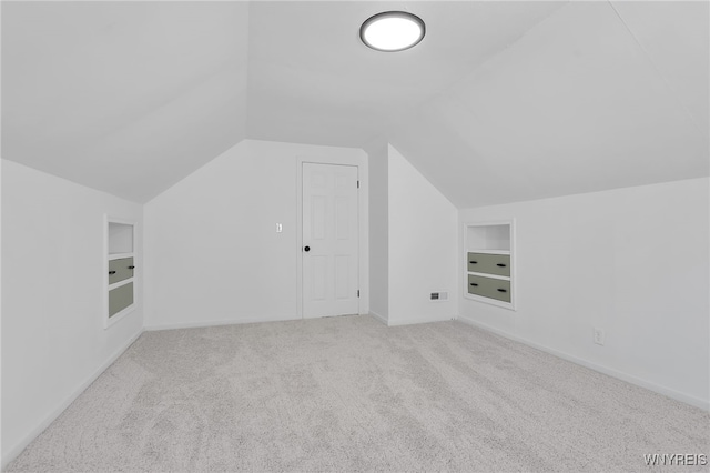 additional living space with built in features, carpet flooring, baseboards, and vaulted ceiling