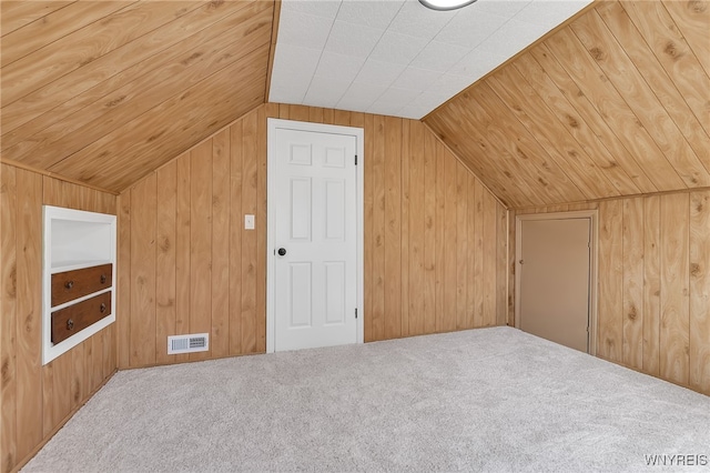 bonus room with vaulted ceiling, visible vents, wooden walls, and carpet floors