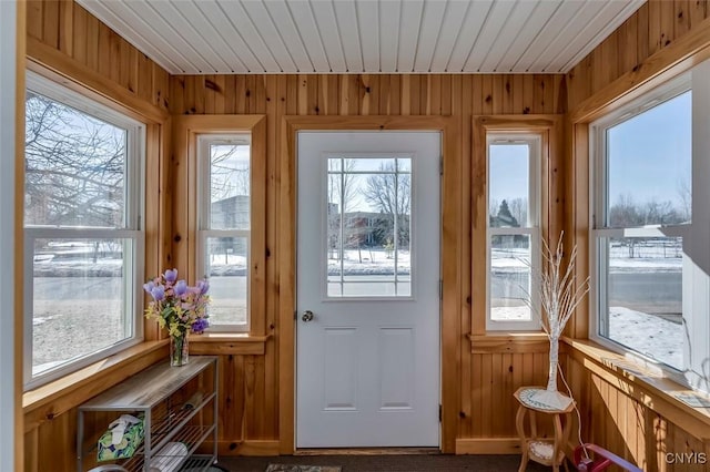 doorway with wood ceiling and wood walls