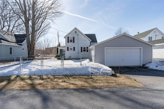 view of front of property featuring an outbuilding, driveway, a detached garage, and fence