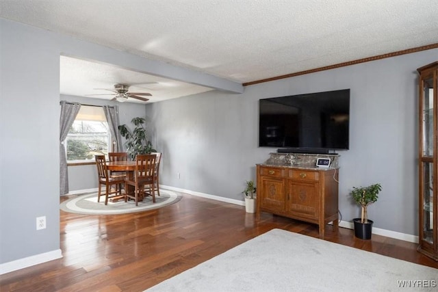 living area featuring ceiling fan, a textured ceiling, baseboards, and wood finished floors