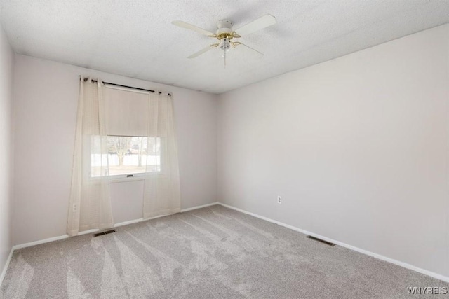 carpeted spare room featuring visible vents, a textured ceiling, and a ceiling fan