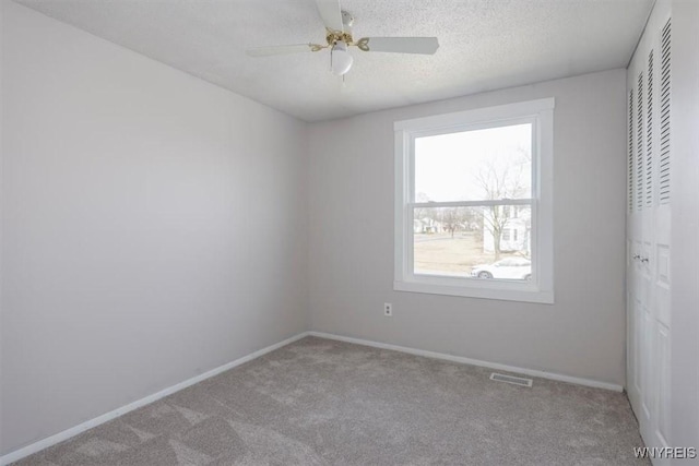 carpeted empty room featuring visible vents, baseboards, and a textured ceiling