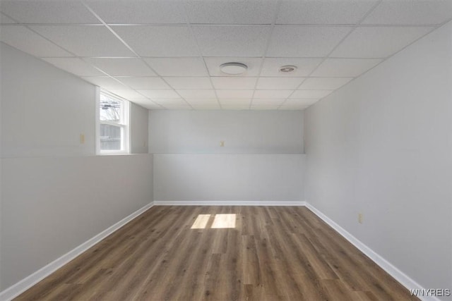 unfurnished room featuring a drop ceiling, baseboards, and wood finished floors