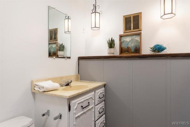 bathroom featuring vanity, toilet, and visible vents