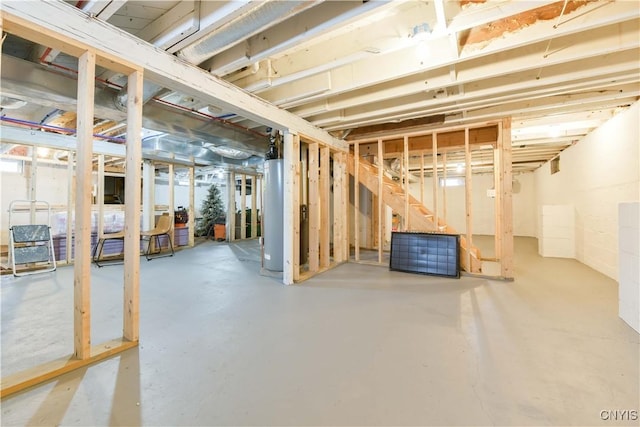 unfinished basement with stairway and gas water heater