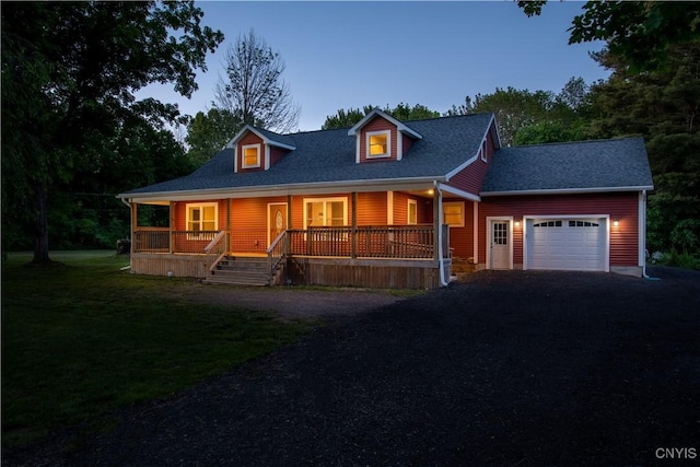 view of front of house featuring a front lawn, aphalt driveway, a porch, roof with shingles, and an attached garage