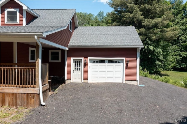 exterior space featuring an attached garage, driveway, and roof with shingles