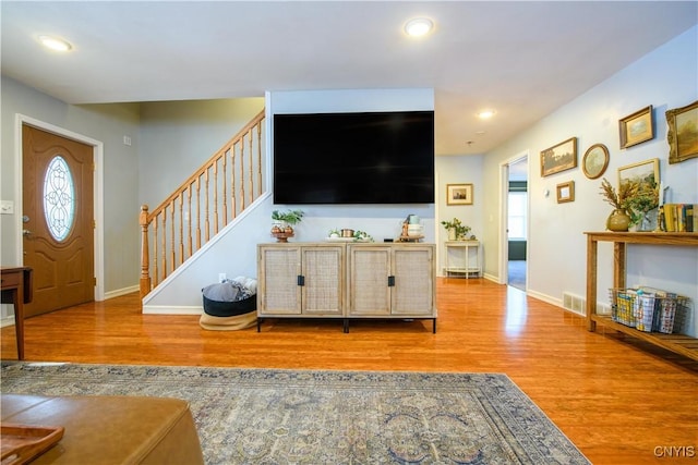 living area with visible vents, baseboards, wood finished floors, and stairs