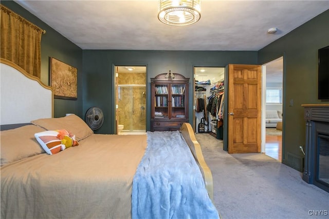 carpeted bedroom with ensuite bath, a spacious closet, and a closet