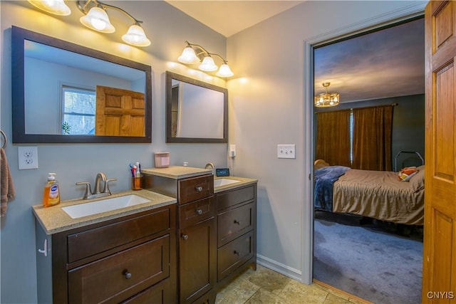 ensuite bathroom featuring double vanity, ensuite bath, baseboards, and a sink