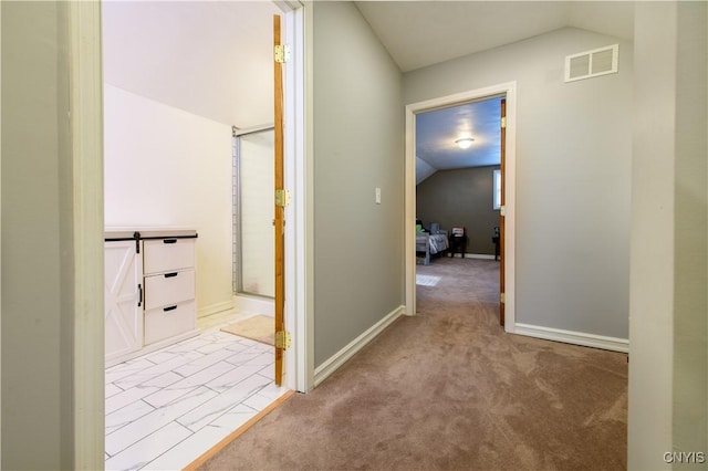 hallway featuring visible vents, carpet floors, baseboards, and vaulted ceiling