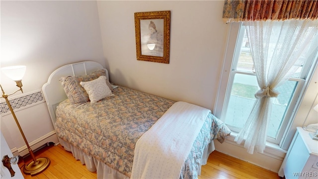 bedroom with a baseboard radiator and wood-type flooring