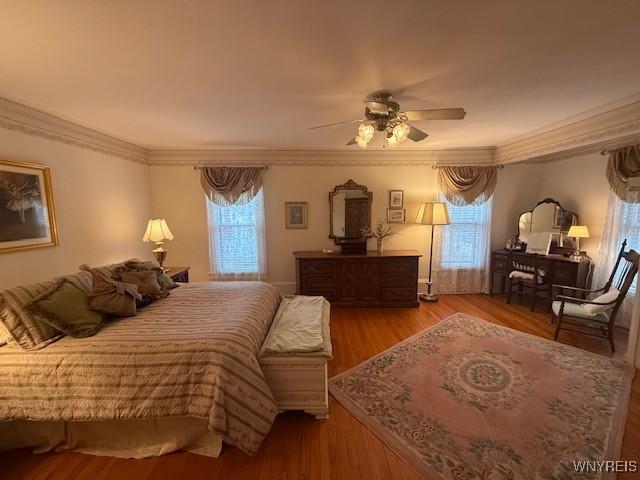 bedroom with ornamental molding, a ceiling fan, and wood finished floors