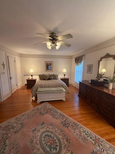 bedroom with a ceiling fan, wood finished floors, baseboards, and ornamental molding