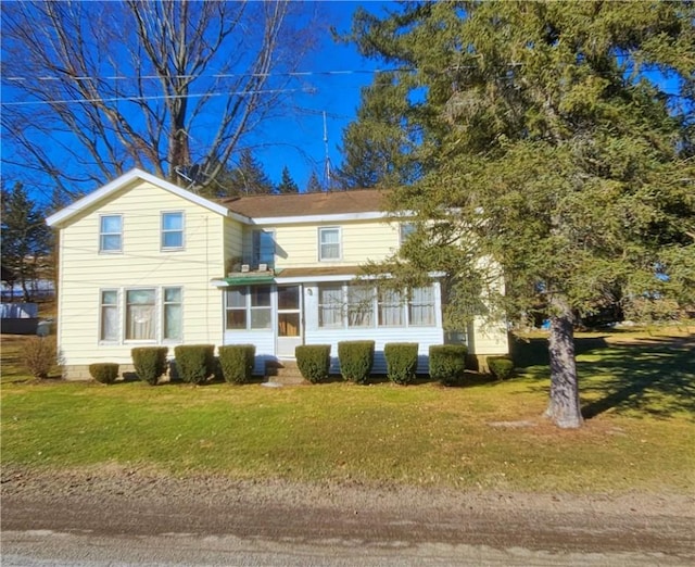 traditional-style home featuring a front lawn and a sunroom