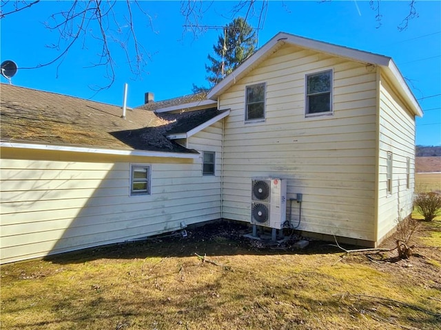 rear view of house with ac unit and a lawn