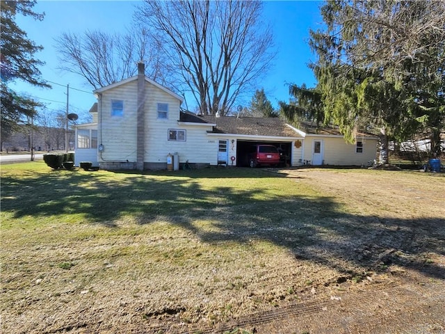 rear view of house featuring a carport, a yard, and driveway