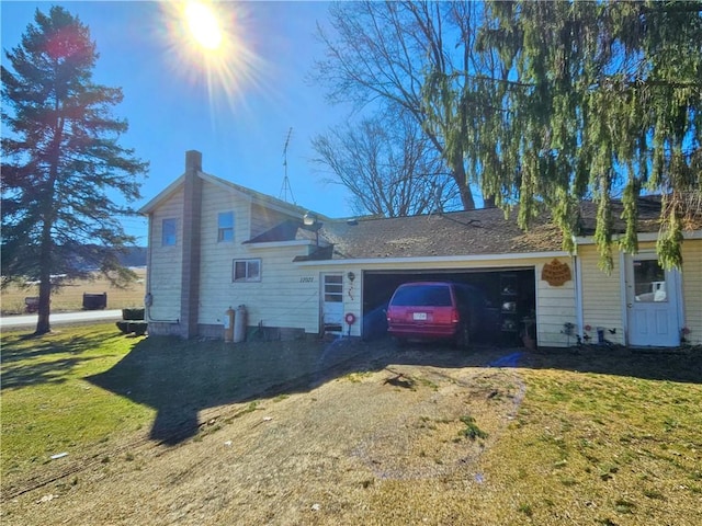 view of side of home featuring an attached garage, a yard, and dirt driveway