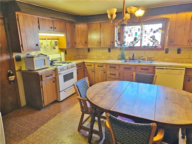 kitchen with a notable chandelier, a sink, white appliances, light countertops, and light floors