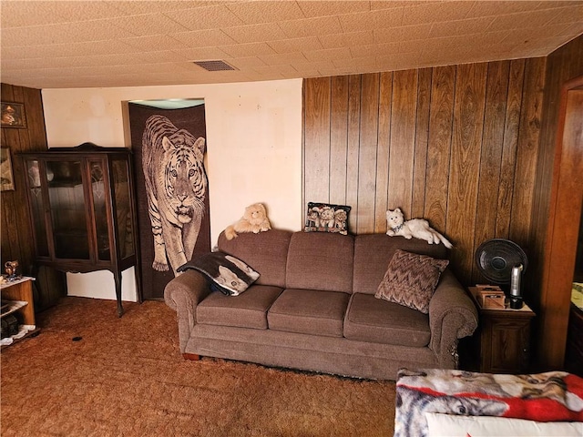 living area featuring visible vents, wooden walls, and carpet