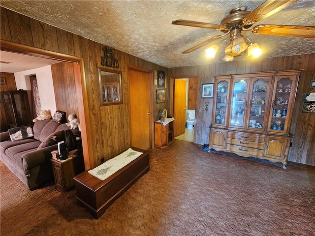 interior space with ceiling fan, wood walls, and a textured ceiling