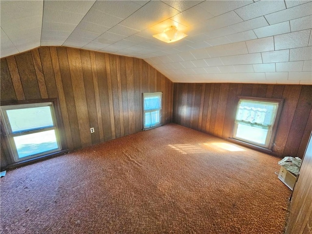 bonus room featuring vaulted ceiling, wood walls, and carpet floors