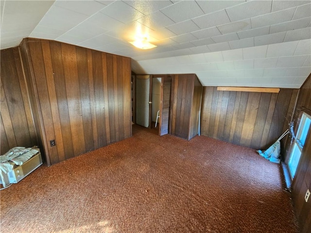 additional living space with wooden walls, lofted ceiling, and carpet