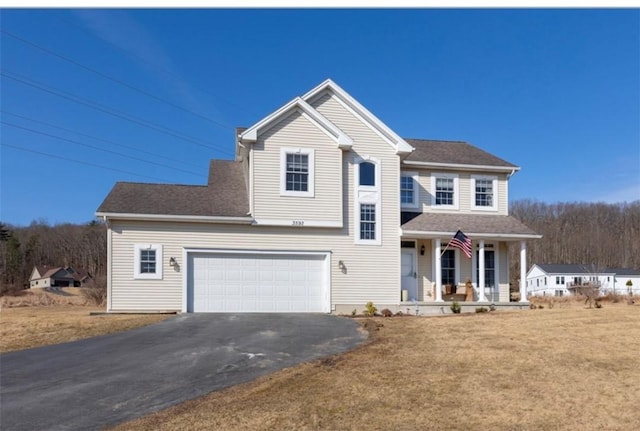 traditional-style home featuring aphalt driveway, covered porch, a front yard, a shingled roof, and a garage