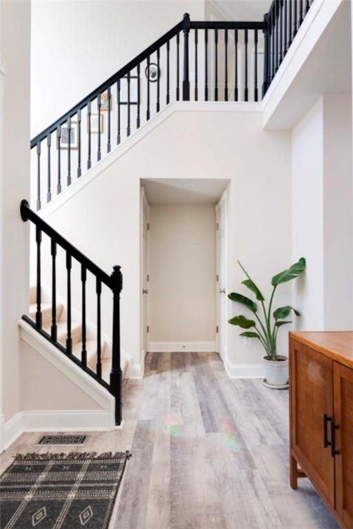 foyer entrance with visible vents, wood finished floors, a high ceiling, baseboards, and stairs